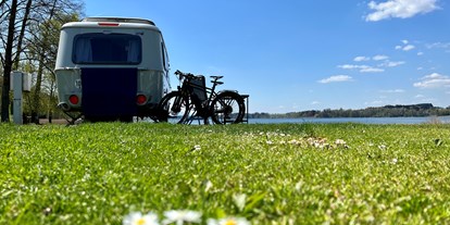 Campingplätze - Reisemobilstellplatz vor der Schranke - Eriba Wohnwagen am Seestellplatz mit Fahrrädern und Gänseblümchen - Camping Stein