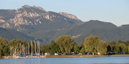 Campingplätze - Oberbayern - Der Campingplatz vom See aus mit der Kampenwand im Hintergrund - Chiemsee-Camping Rödlgries